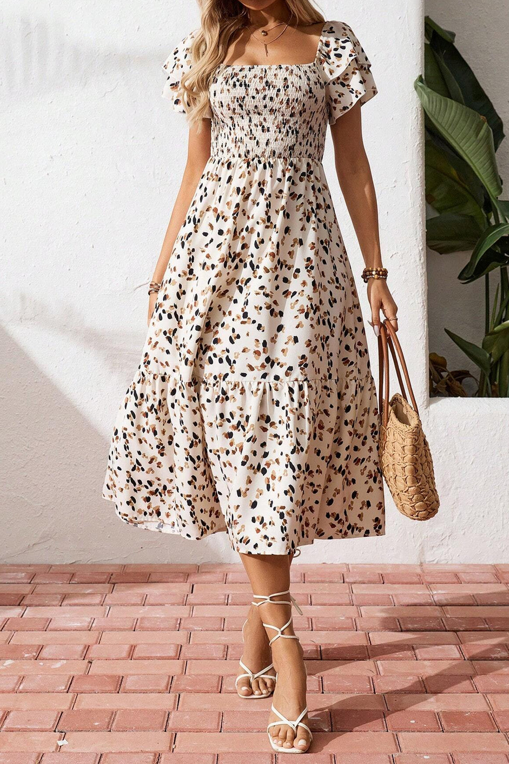 Vestido corto beige con estampado floral discreto, cuello cuadrado fruncido y mangas cortas con volantes.