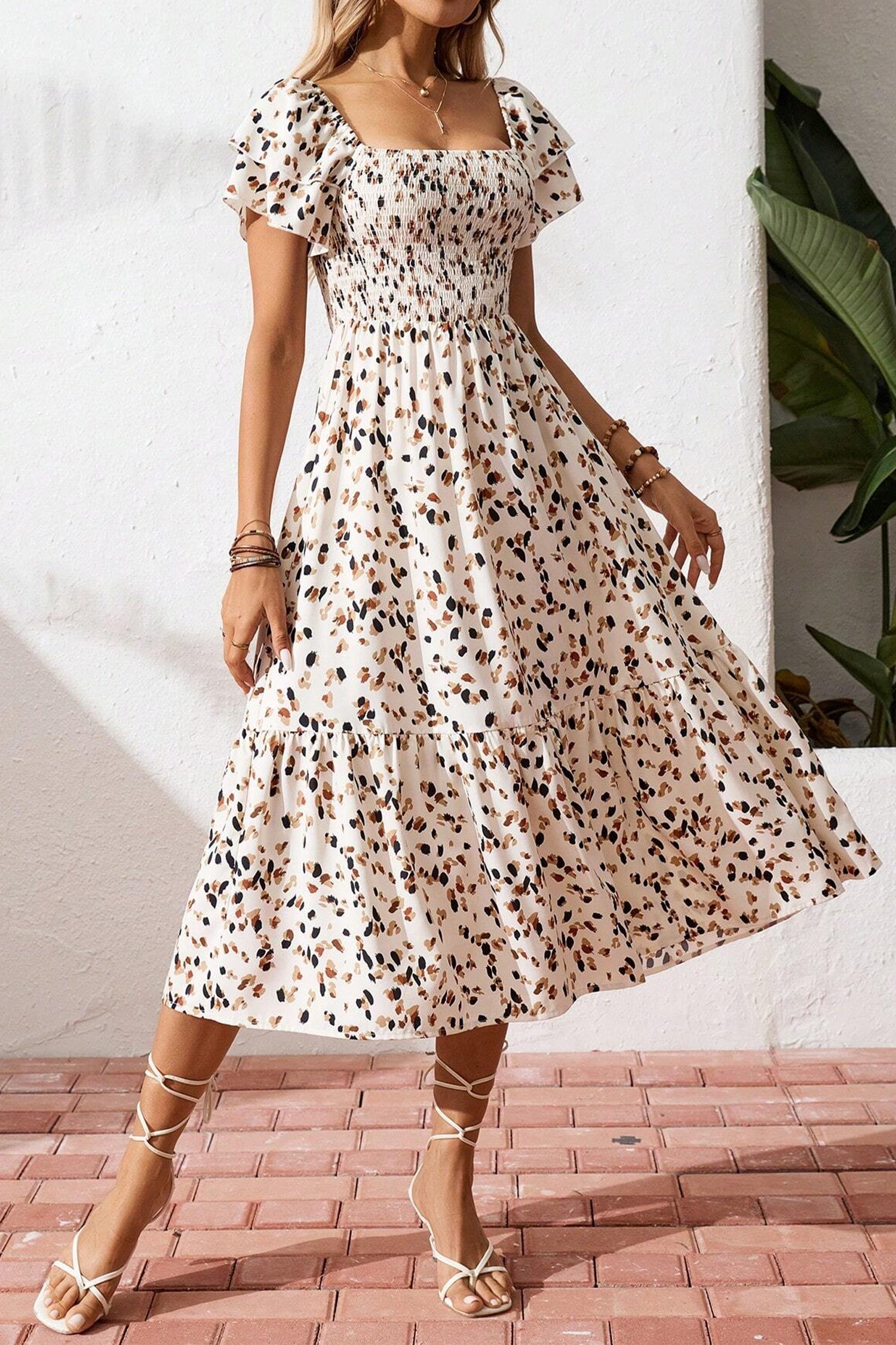 Vestido corto beige con estampado floral discreto, cuello cuadrado fruncido y mangas cortas con volantes.
