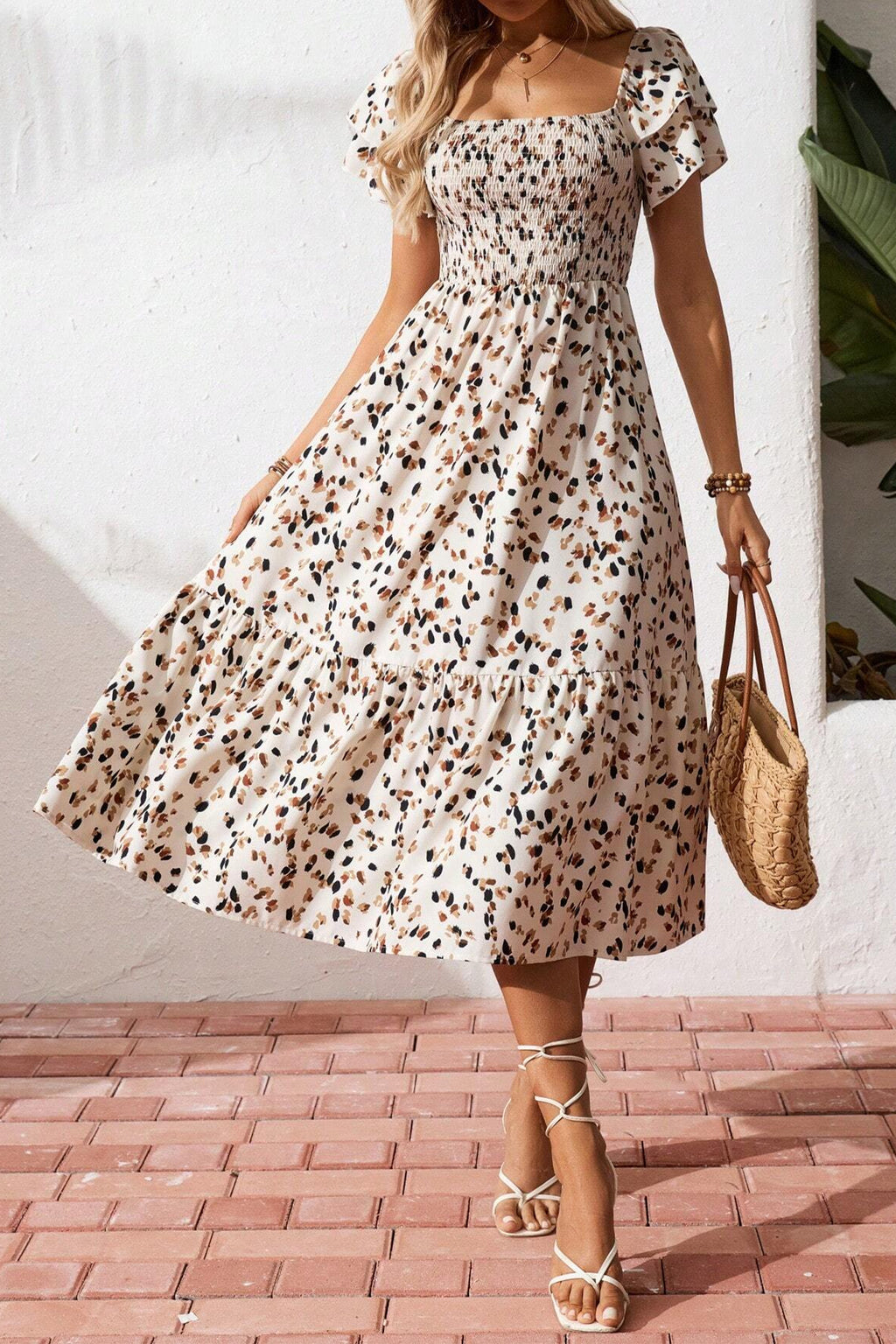 Vestido corto beige con estampado floral discreto, cuello cuadrado fruncido y mangas cortas con volantes.