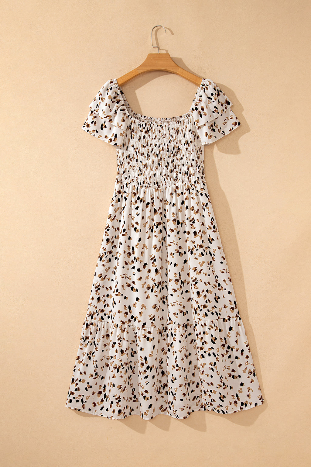 Vestido corto beige con estampado floral discreto, cuello cuadrado fruncido y mangas cortas con volantes.
